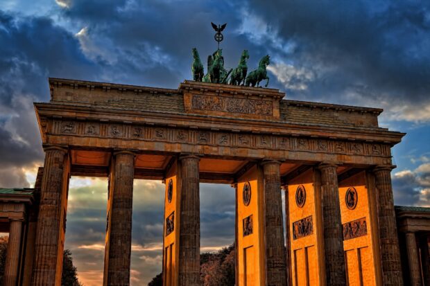 The Brandenburg Gate in Berlin is illuminated by sunset light with dramatic clouds, HD Desktop Wallpaper