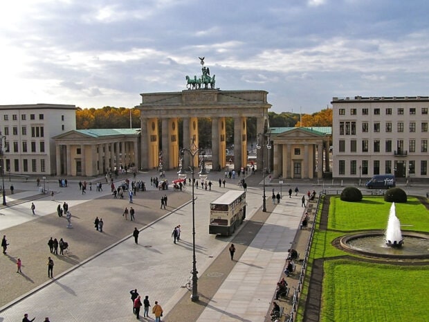 The Brandenburg Gate in Berlin stands with tourists and a tour bus nearby, HD Desktop Wallpaper