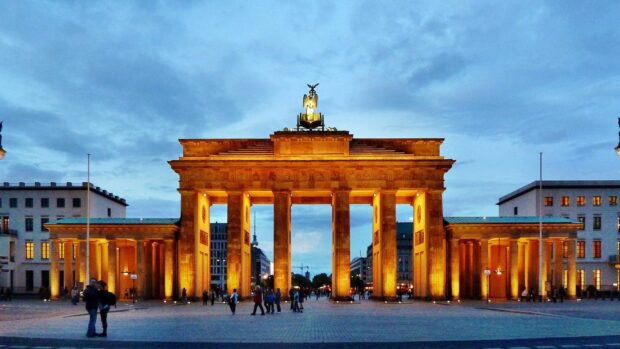 The Brandenburg Gate in Berlin stands illuminated with people walking nearby at dusk, HD Desktop Wallpaper