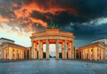 The Brandenburg Gate in Berlin stands illuminated under a dramatic sunset sky, HD Desktop Wallpaper