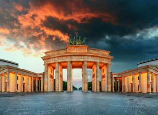 The Brandenburg Gate in Berlin stands illuminated under a dramatic sunset sky, HD Desktop Wallpaper