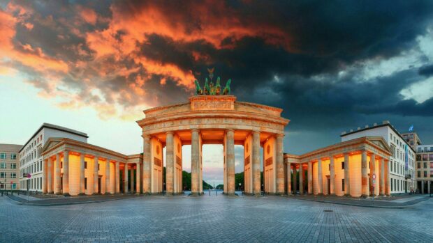 The Brandenburg Gate in Berlin stands illuminated under a dramatic sunset sky, HD Desktop Wallpaper