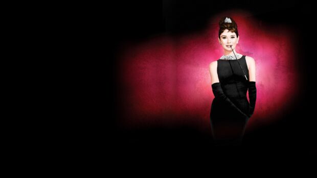 Audrey Hepburn in Breakfast At Tiffanys wearing a black dress and tiara with a cigarette holder