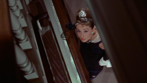 Woman from Breakfast At Tiffanys looking up the staircase holding sunglasses