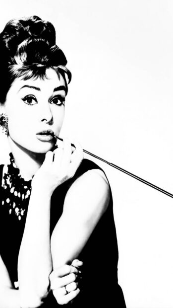 A classic Breakfast At Tiffanys portrait of a woman holding a cigarette holder in black and white style