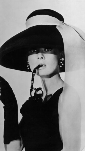 Audrey Hepburn in Breakfast At Tiffanys wearing a large hat and holding a cigarette holder