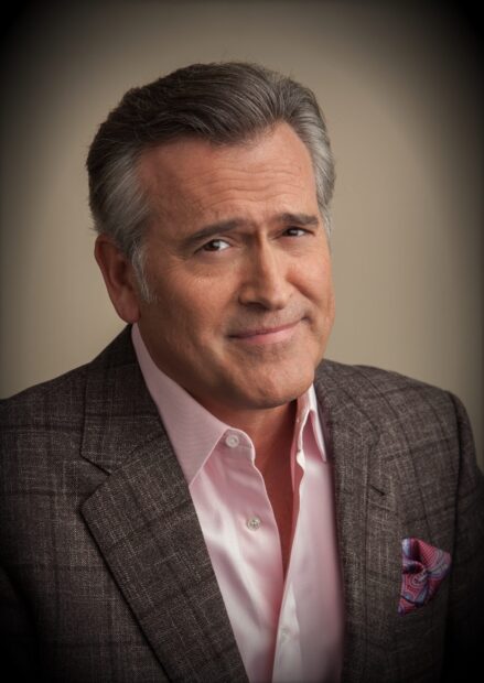 Bruce Campbell is wearing a brown checked suit and pink shirt with a smile, 2K Mobile Wallpaper