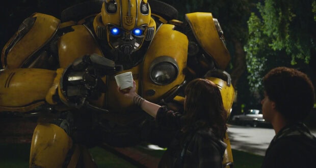 A girl offering an object to Bumblebee Transformers in a night scene
