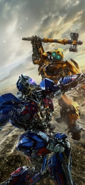 Bumblebee robot raising a large hammer in a battle against another blue and red robot under a cloudy sky