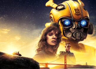 Bumblebee robot with glowing blue eyes stands behind a young woman and a man near the Golden Gate Bridge at sunset