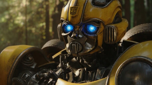 Close up of Bumblebee robot with glowing blue eyes in a forest background wallpaper