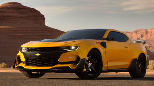 A bright yellow sports car inspired by Bumblebee is parked on a desert road with rocky cliffs in the background