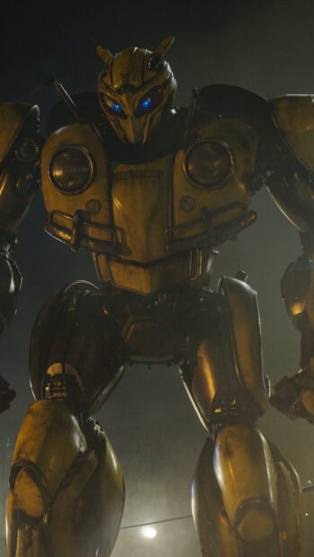 A close up of the Bumblebee robot with glowing blue eyes in a dark environment