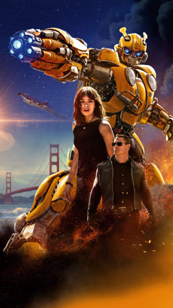 Bumblebee robot stands protectively behind two humans with the Golden Gate Bridge in the background