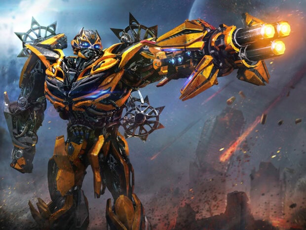 Bumblebee robot is in battle mode firing glowing cannons amid a smoky, explosive warzone