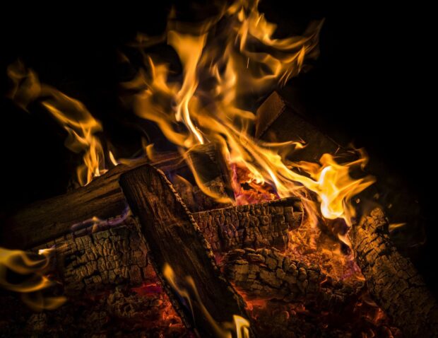 The burning firewood shows warm and bright flames in the dark, 2K Desktop Wallpaper