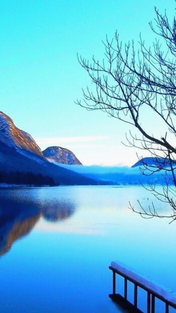 A calm lake reflects surrounding mountains under a clear blue sky in serene scenery wallpapers, HD Mobile Wallpaper