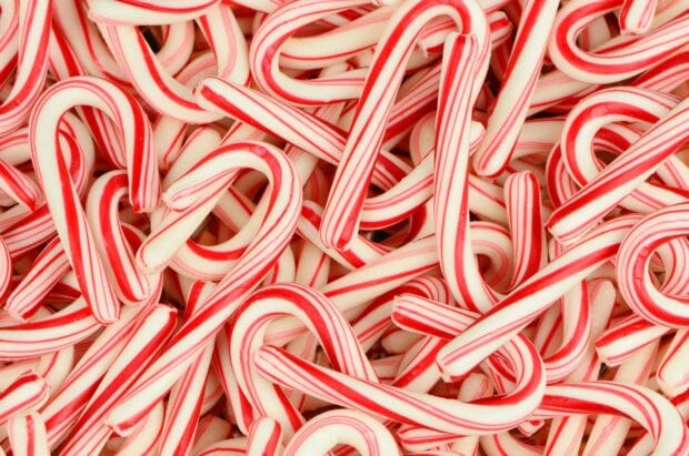 A close up view of multiple candy cane sticks with red and white stripes piled together