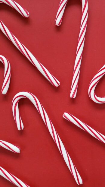 Red striped candy cane sticks arranged on a red surface