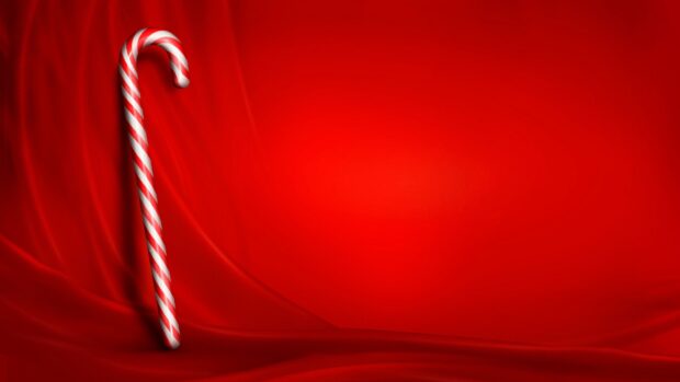 A candy cane standing upright on red satin fabric with smooth folds and lighting effects