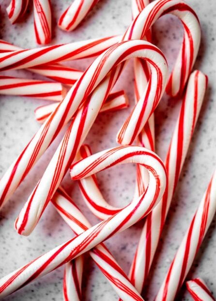 Red and white candy cane sticks arranged on a speckled surface