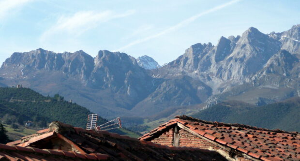 Traditional rooftops in front of the Cantabrian Mountains under a clear sky