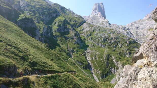A scenic view of Cantabrian Mountains with green slopes and rocky peaks under clear blue sky