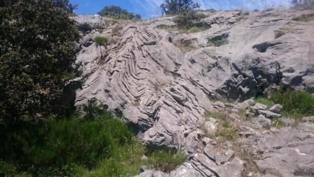 Folded rock formations with greenery in the Cantabrian Mountains landscape