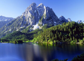 Stunning Cantabrian Mountains with lush green forest and clear lake under blue sky