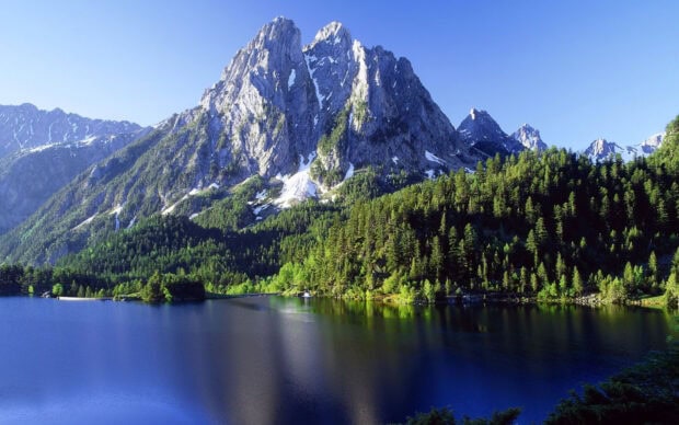 Stunning Cantabrian Mountains with lush green forest and clear lake under blue sky