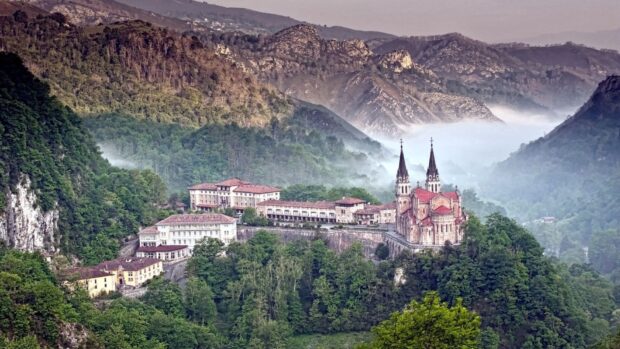 Ancient Cantabrian Mountains landscape with mist and historic buildings nestled among trees
