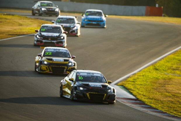 Black and yellow car race leading other cars on a curved track during a car race