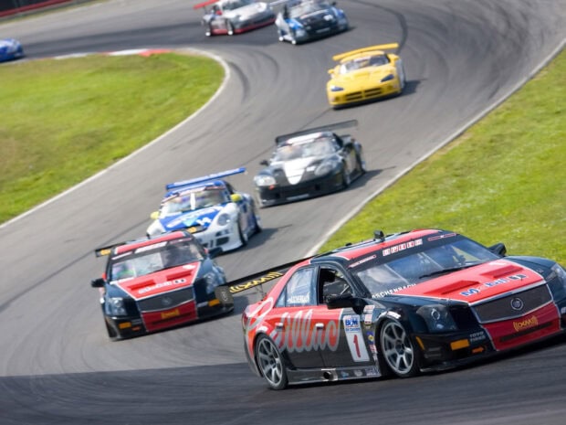 Racing cars compete intensely on a curved asphalt track during a car race event