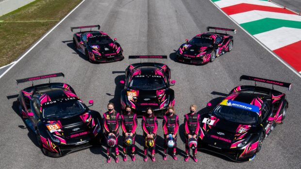 Racing team standing with race cars on track in a car race