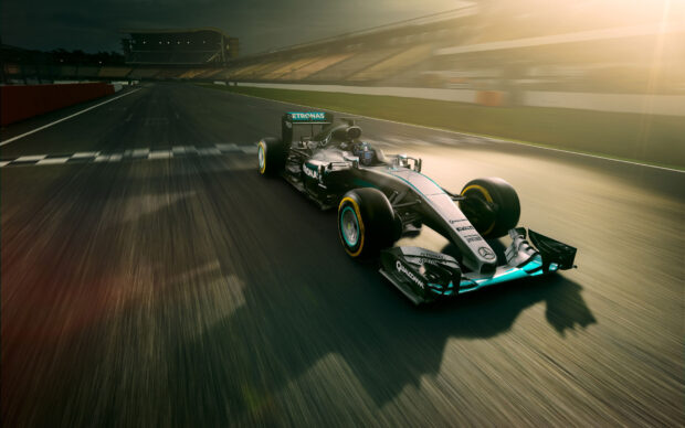 A Formula One car race on a speedway during sunset with motion blur effect