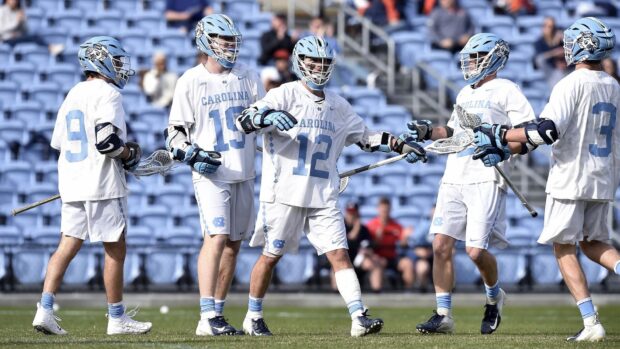 Five players in Carolina lacrosse uniforms are gathered during a game, HD Desktop Wallpaper