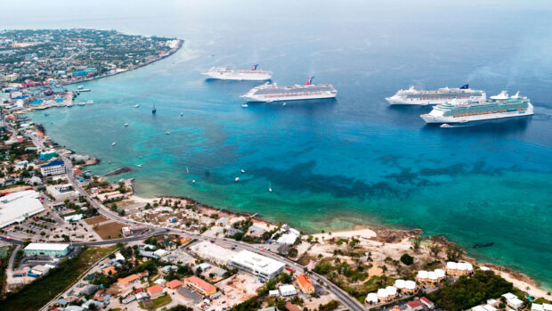 Aerial view of cruise ships near the Cayman Islands coastline with clear turquoise water and urban area