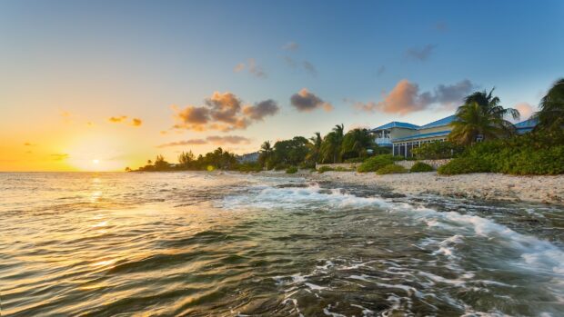 Ocean waves gently crashing on the shore of Cayman Islands with a sunset sky