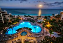 A stunning view of the Cayman Islands resort with a glowing pool and ocean under the moonlight
