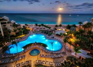 A stunning view of the Cayman Islands resort with a glowing pool and ocean under the moonlight