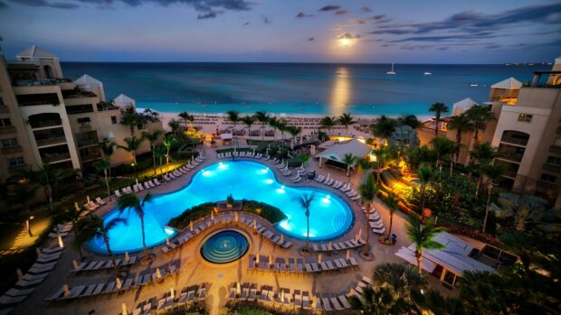 A stunning view of the Cayman Islands resort with a glowing pool and ocean under the moonlight