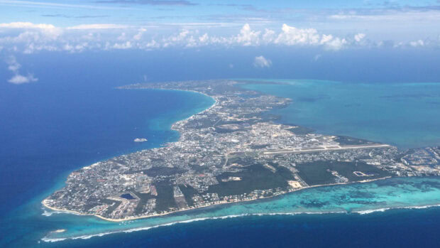 Aerial view of Cayman Islands showing coastline and urban areas with clear turquoise water around the island