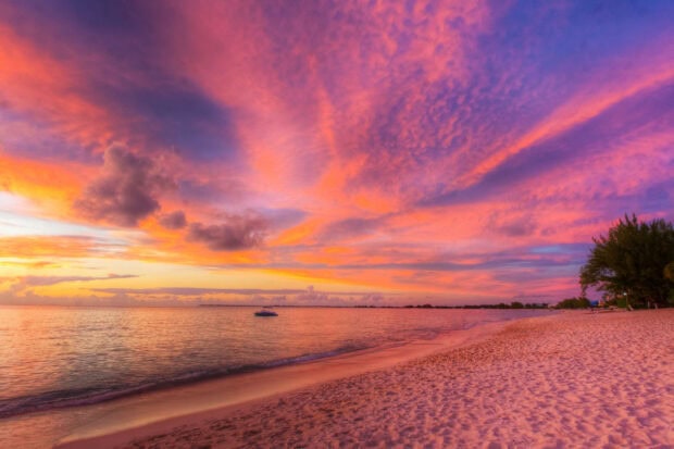 Vibrant sky over the Cayman Islands beach at sunset with calm sea and sandy shore