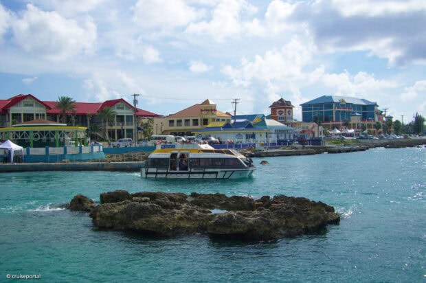 A boat near colorful buildings in Cayman Islands under a cloudy sky