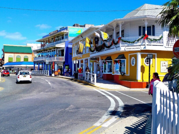 Colorful Cayman Islands street with shops and people under a clear blue sky