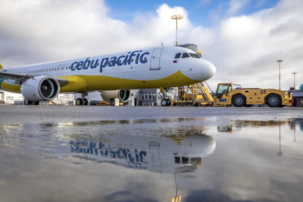 A Cebu Pacific Air plane is parked at the airport with reflections in the water, HD Desktop Wallpaper