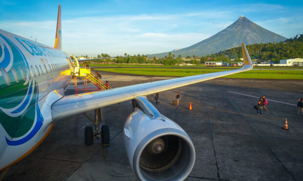 A Cebu Pacific Air plane is parked on the runway with Mayon Volcano in the background, HD Desktop Wallpaper
