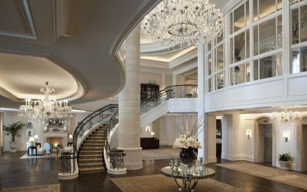 Elegant chandelier lighting in a spacious luxurious hall with grand staircase and decorative vase   Copy