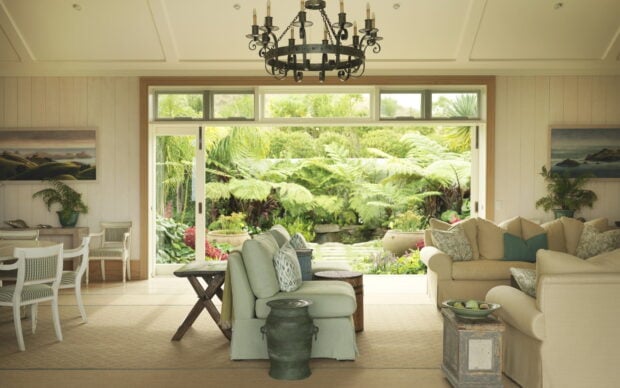A vintage chandelier hanging over a bright living room with a garden view through sliding glass doors