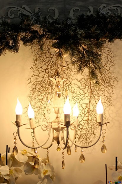 Elegant chandelier with decorative branches and flowers hanging in warm light